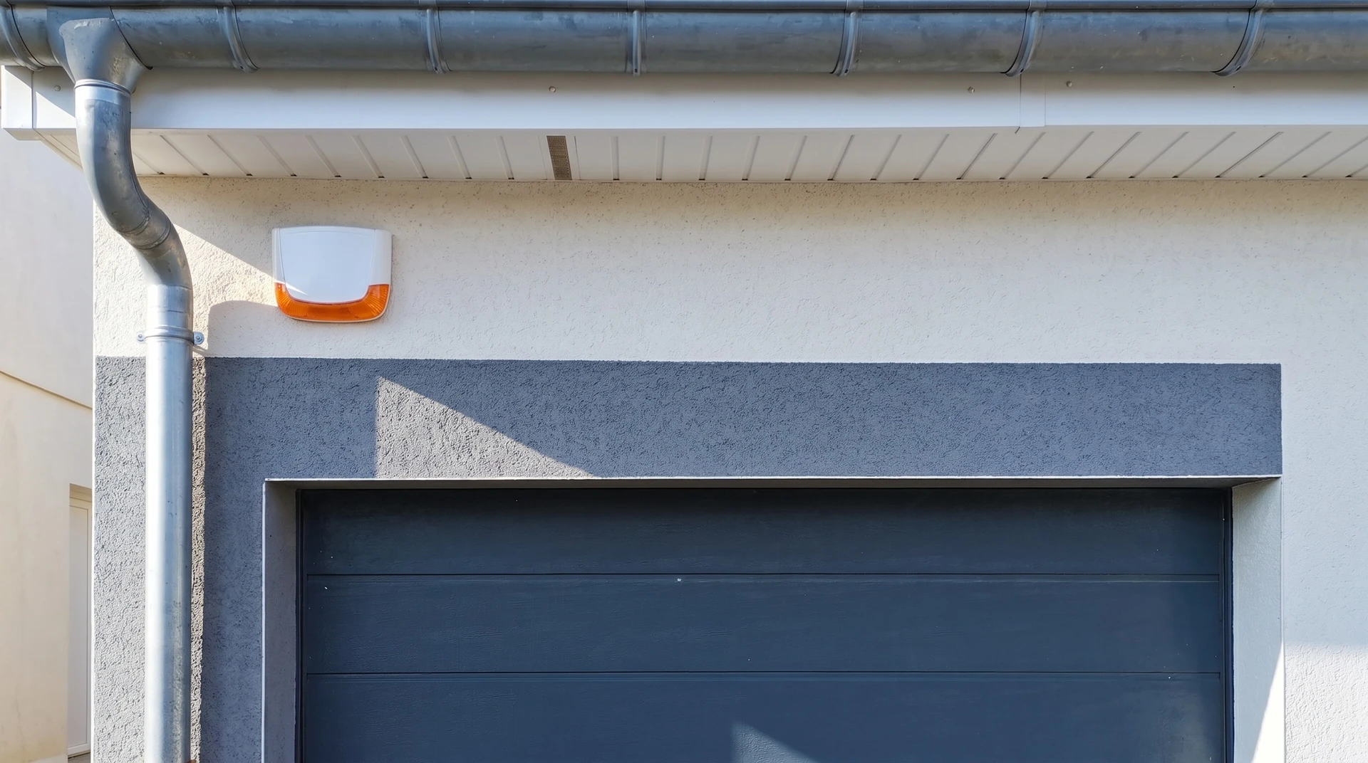 Technicien en uniforme de travail gris et casquette rouge installant une caméra de surveillance IP sur un mur intérieur